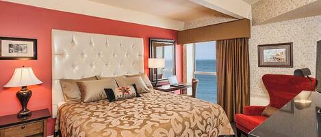 Une chambre d’hôtel avec un grand lit, un bureau, une chaise et une vue sur la mer.