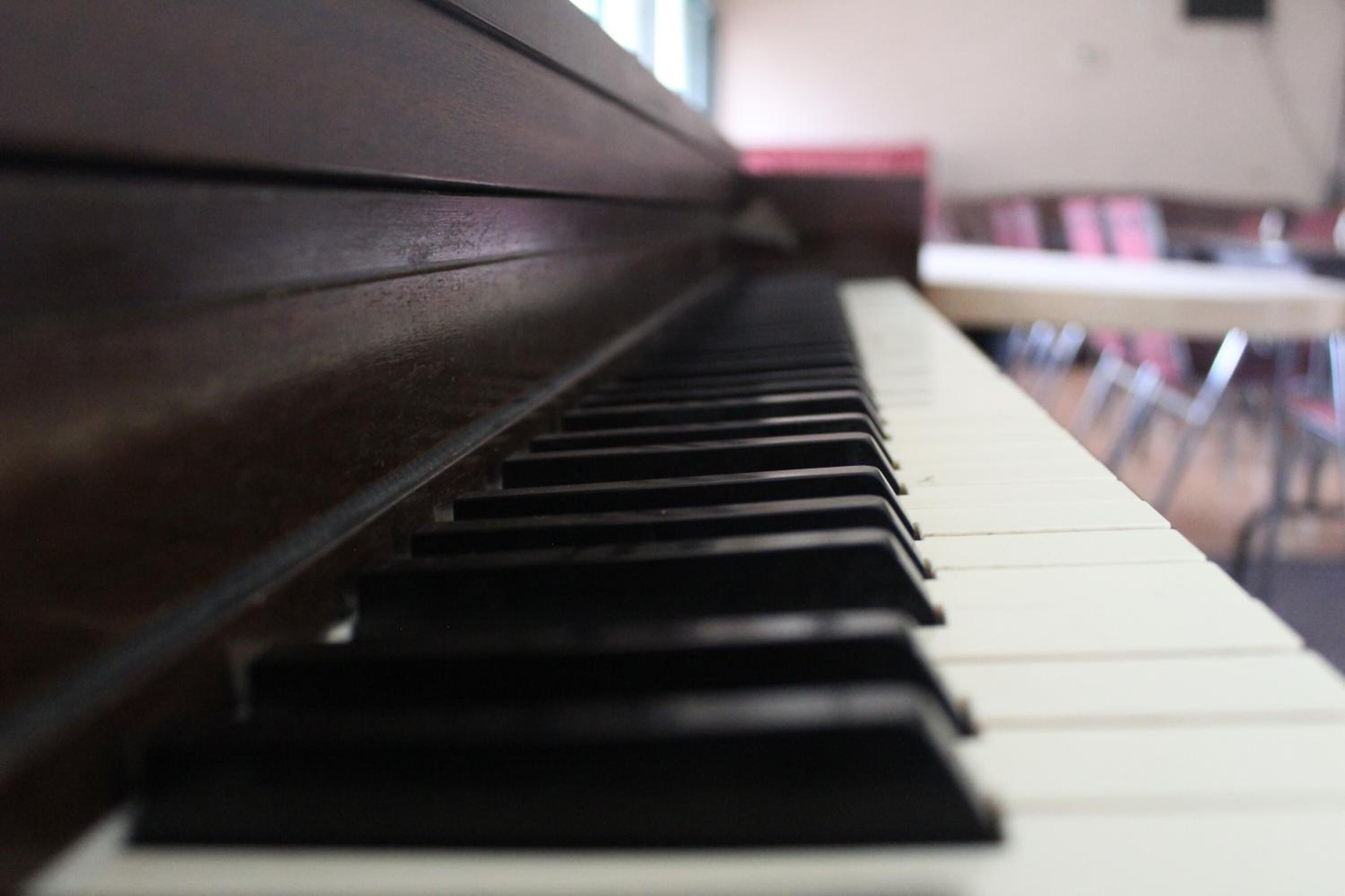 A piano with a dark wooden finish and white and black keys.