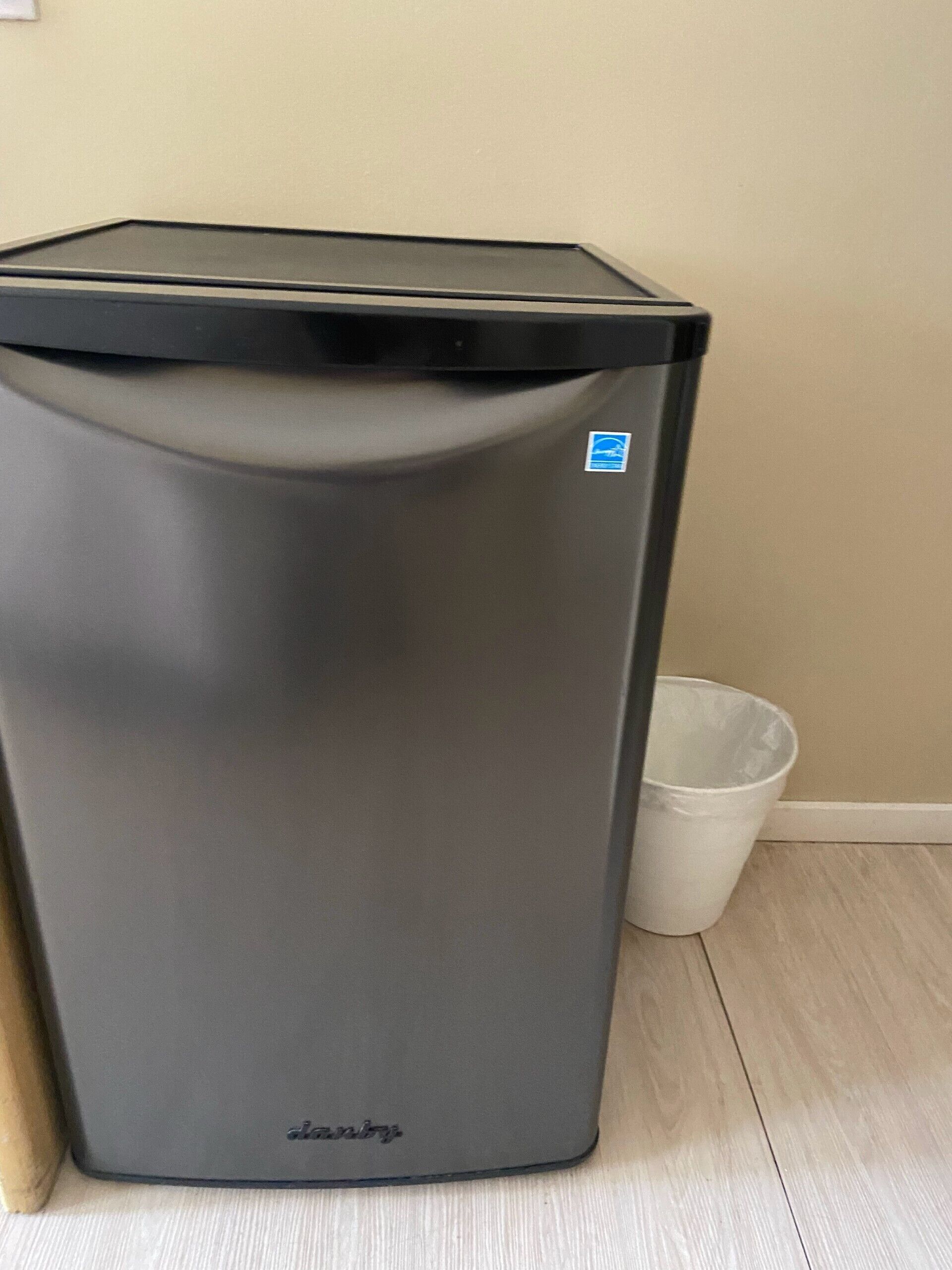 Un basurero gris con tapa y un pequeño símbolo azul de reciclaje, con el nombre de la marca 'danny' en la parte frontal.