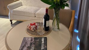A round table with a magazine, a bottle of wine, a vase with red roses, and a woven placemat. - Slumber Lodge Motel (Hope)