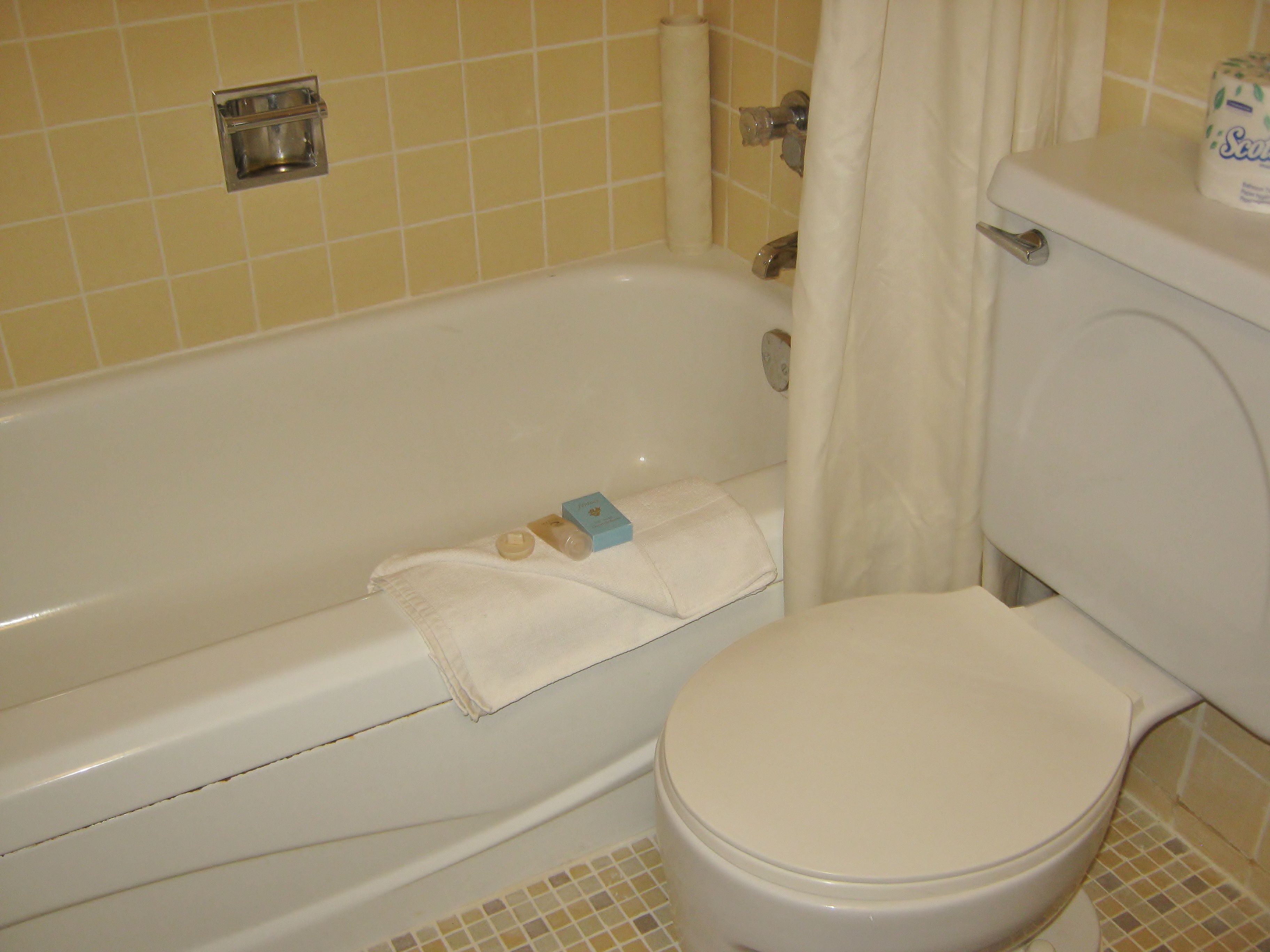 Une salle de bain avec une baignoire blanche, des toilettes et un rideau de douche.