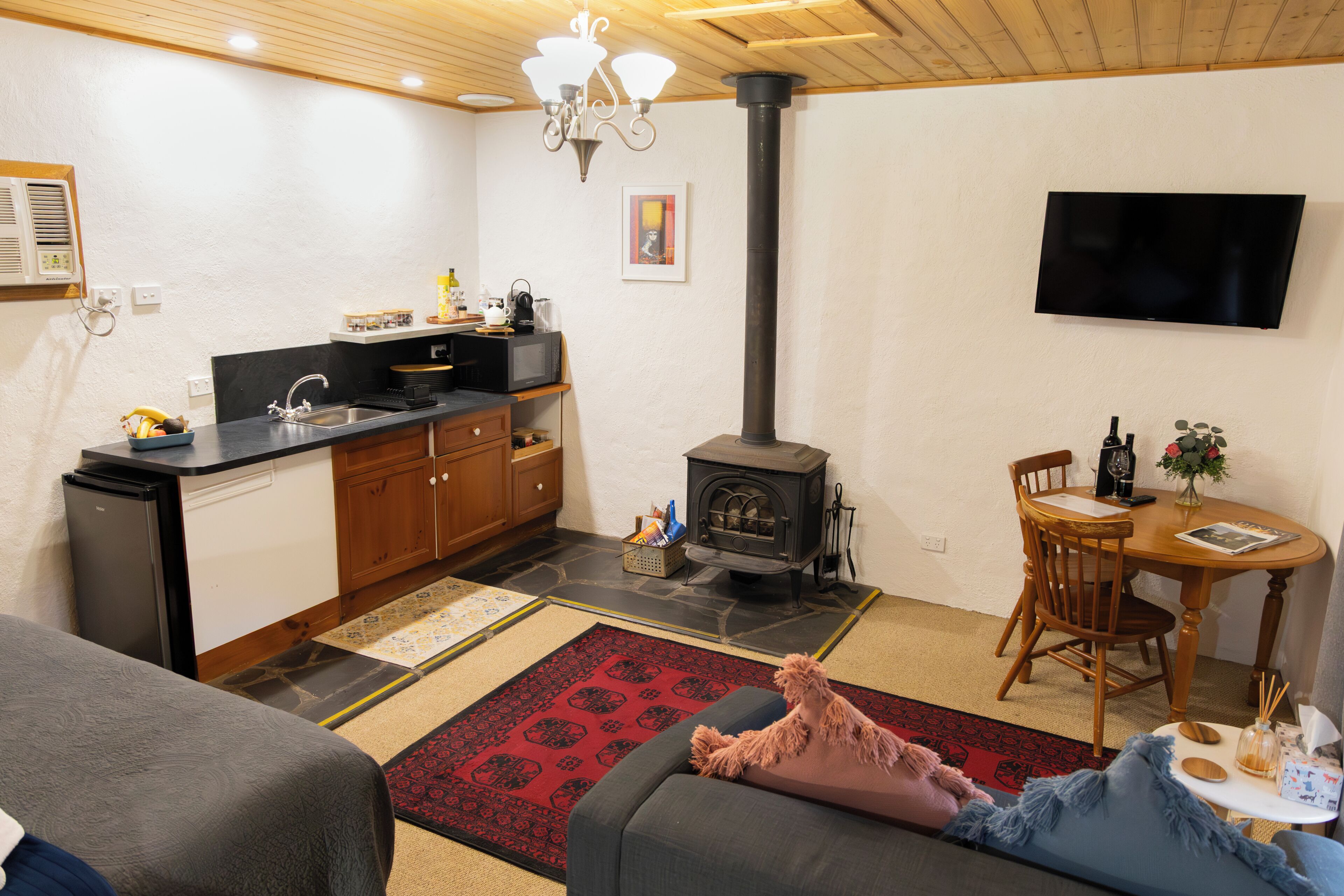 A compact living space with a kitchenette, a fireplace, a dining area, and a TV mounted on the wall.