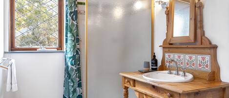 A bathroom with a wooden vanity, a sink, a mirror, and a shower with a glass door.