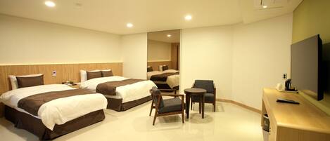 Habitación de hotel con dos camas, un escritorio, una silla y un televisor.