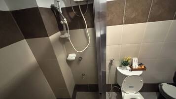 A bathroom with a shower, toilet, and a small shelf with toiletries.
