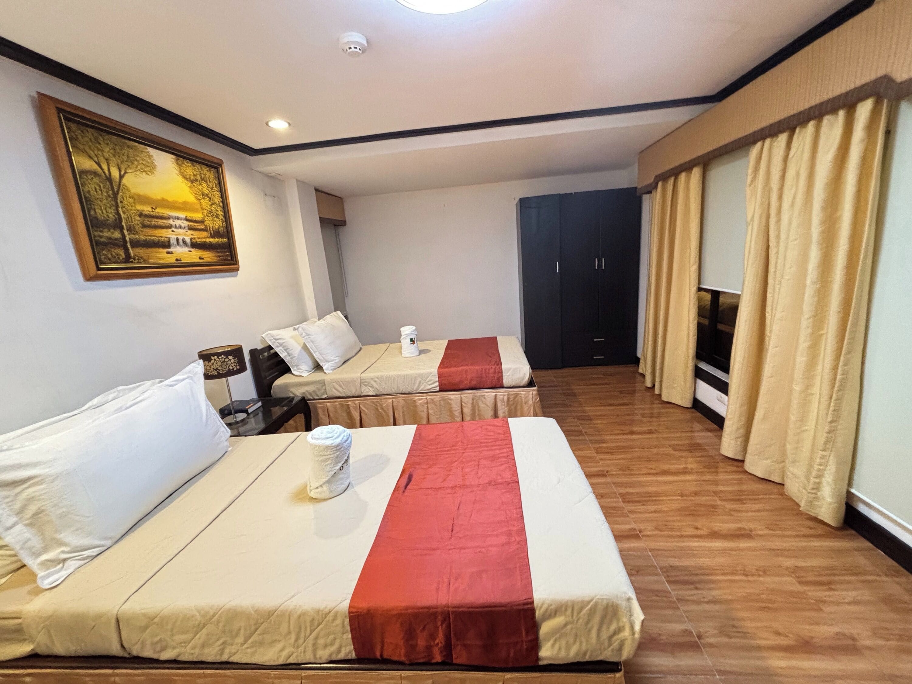 Una habitación de hotel con dos camas, un cuadro en la pared, un armario y un televisor.