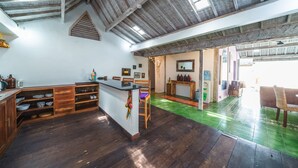 A spacious kitchen with wooden cabinets, a central island, and a green floor. - Villa West (Seminyak)