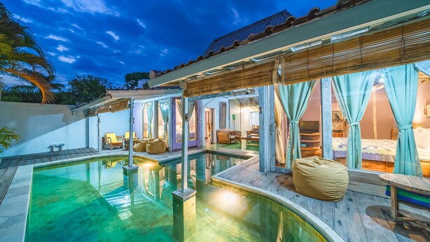 A pool area with a wooden deck, a bean bag chair, and a covered seating area with curtains. - Villa West (Seminyak)