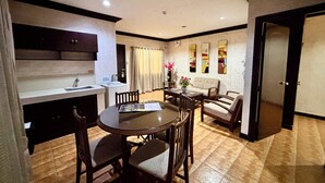 A dining area with a round table and chairs, a kitchen with a sink and cabinets, and a living area with a sofa and decorative wall art. - D'Japanese Tunnel Family Resort (Davao)