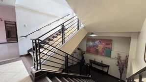 A staircase with a metal railing, a potted plant, and a painting on the wall. - D'Japanese Tunnel Family Resort (Davao)