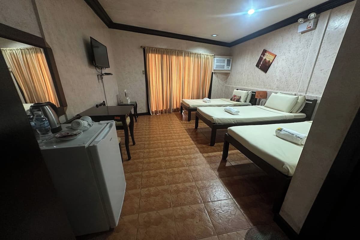 A hotel room with two single beds, a desk with a chair, a washing machine, and a television on the wall.