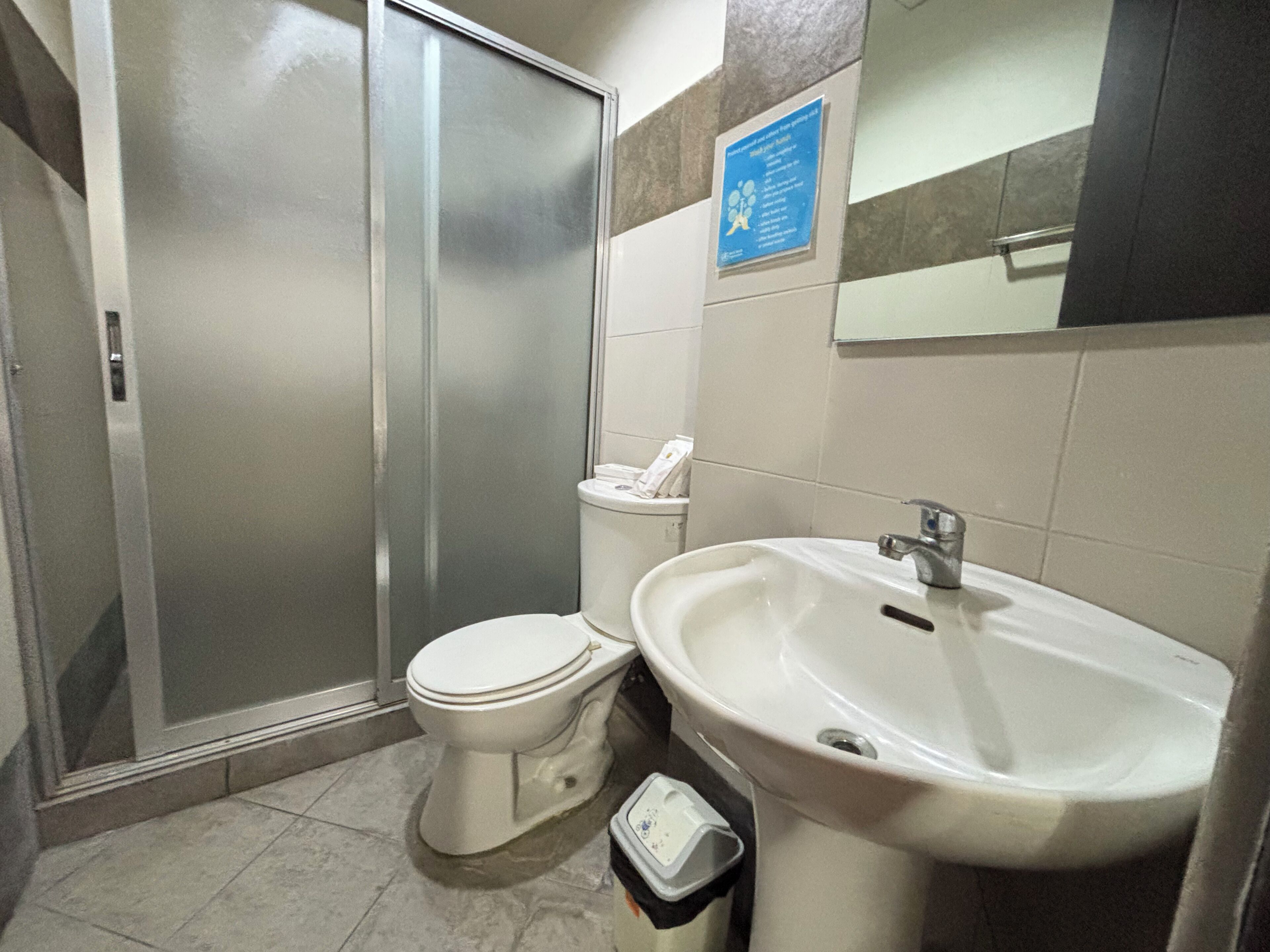 A bathroom with a toilet, sink, and a glass shower enclosure.