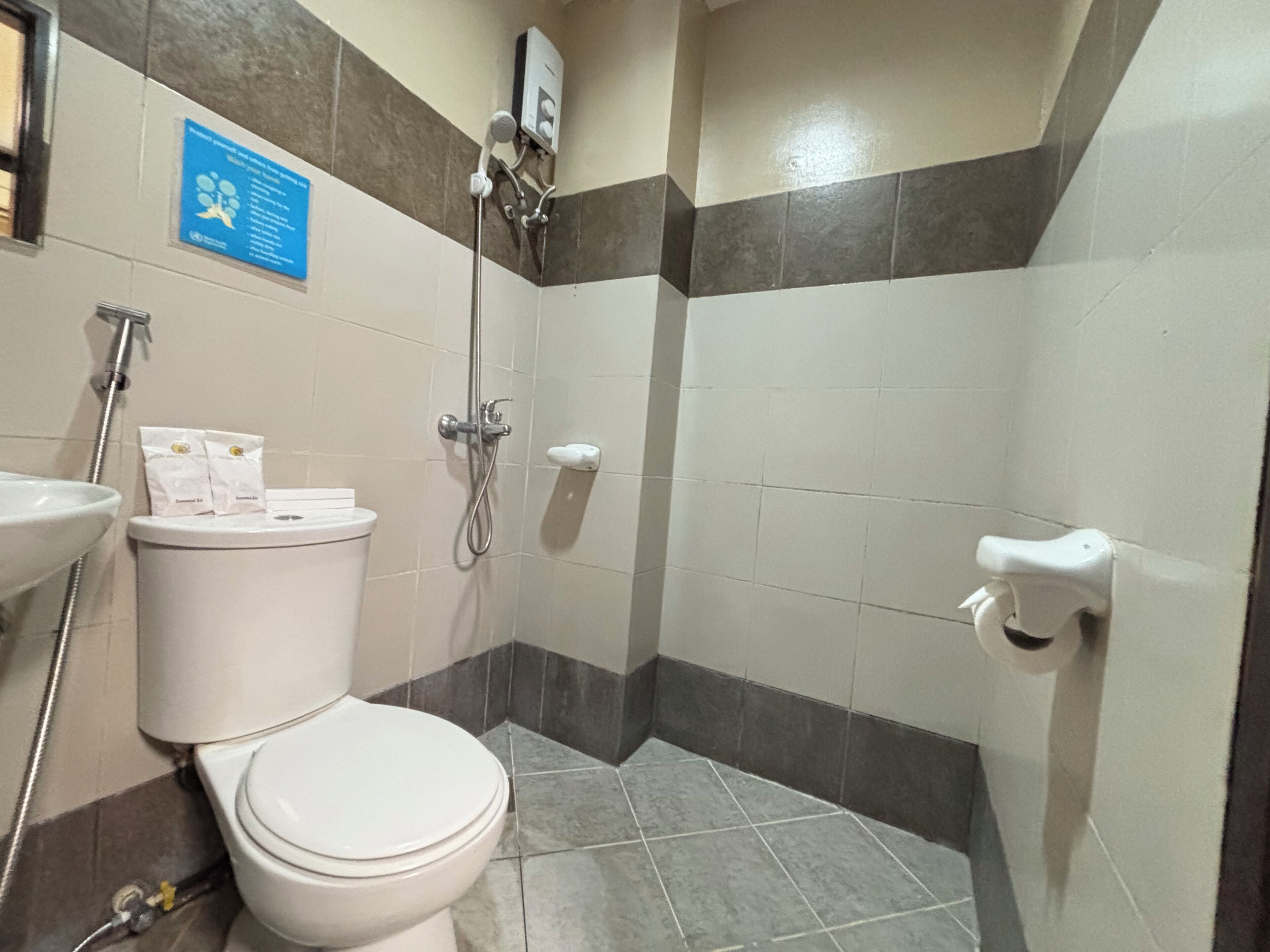 A bathroom with a toilet, sink, shower, and a sign on the wall.