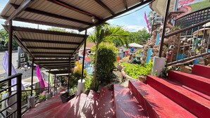 A covered outdoor area with a staircase leading to a higher level, surrounded by greenery and a mural. - D'Japanese Tunnel Family Resort (Davao)