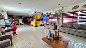 A hotel lobby with a reception desk, seating area, and a large screen displaying information. - D'Japanese Tunnel Family Resort (Davao)