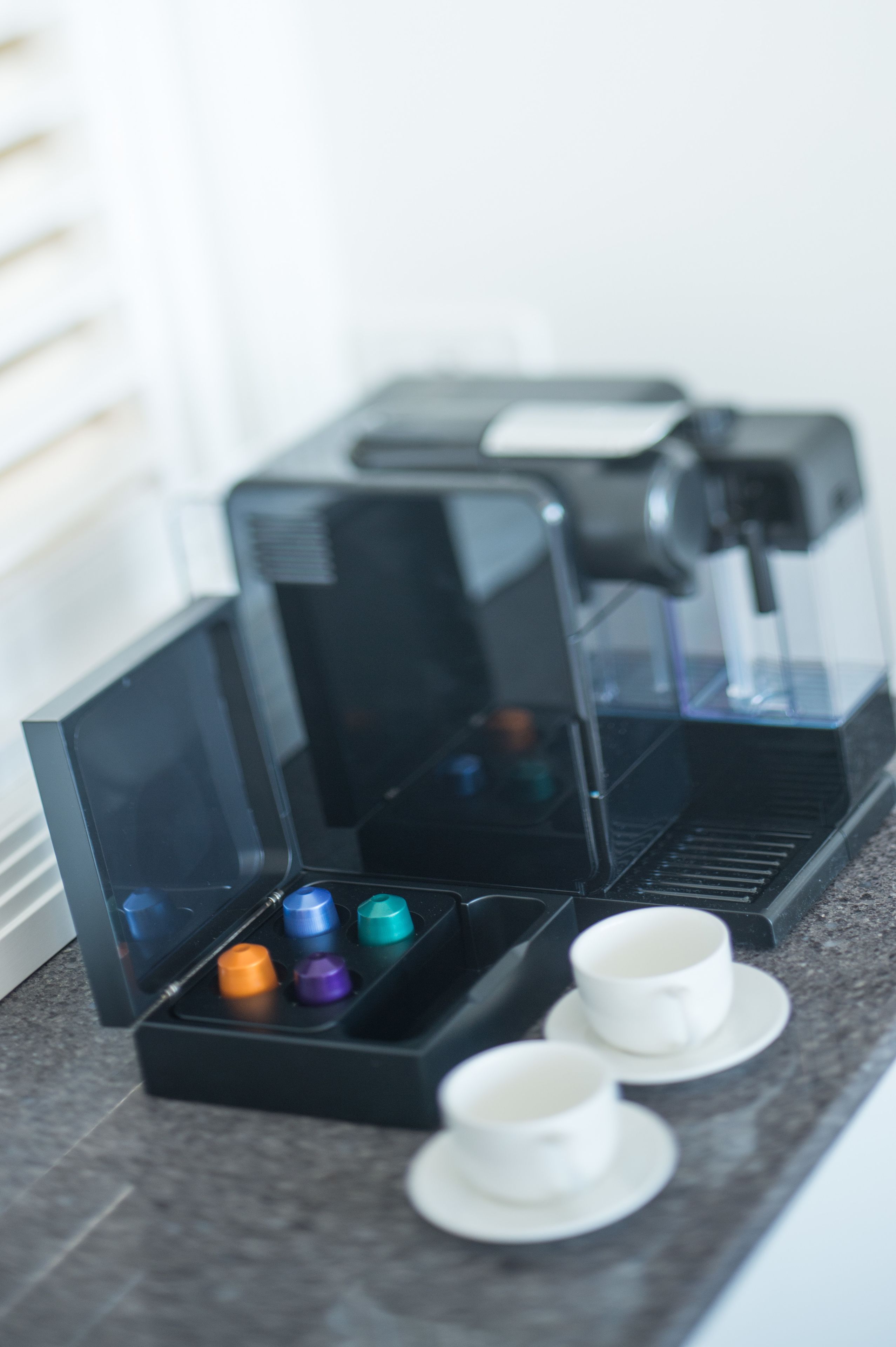 A coffee machine with a transparent water reservoir and a drip tray.