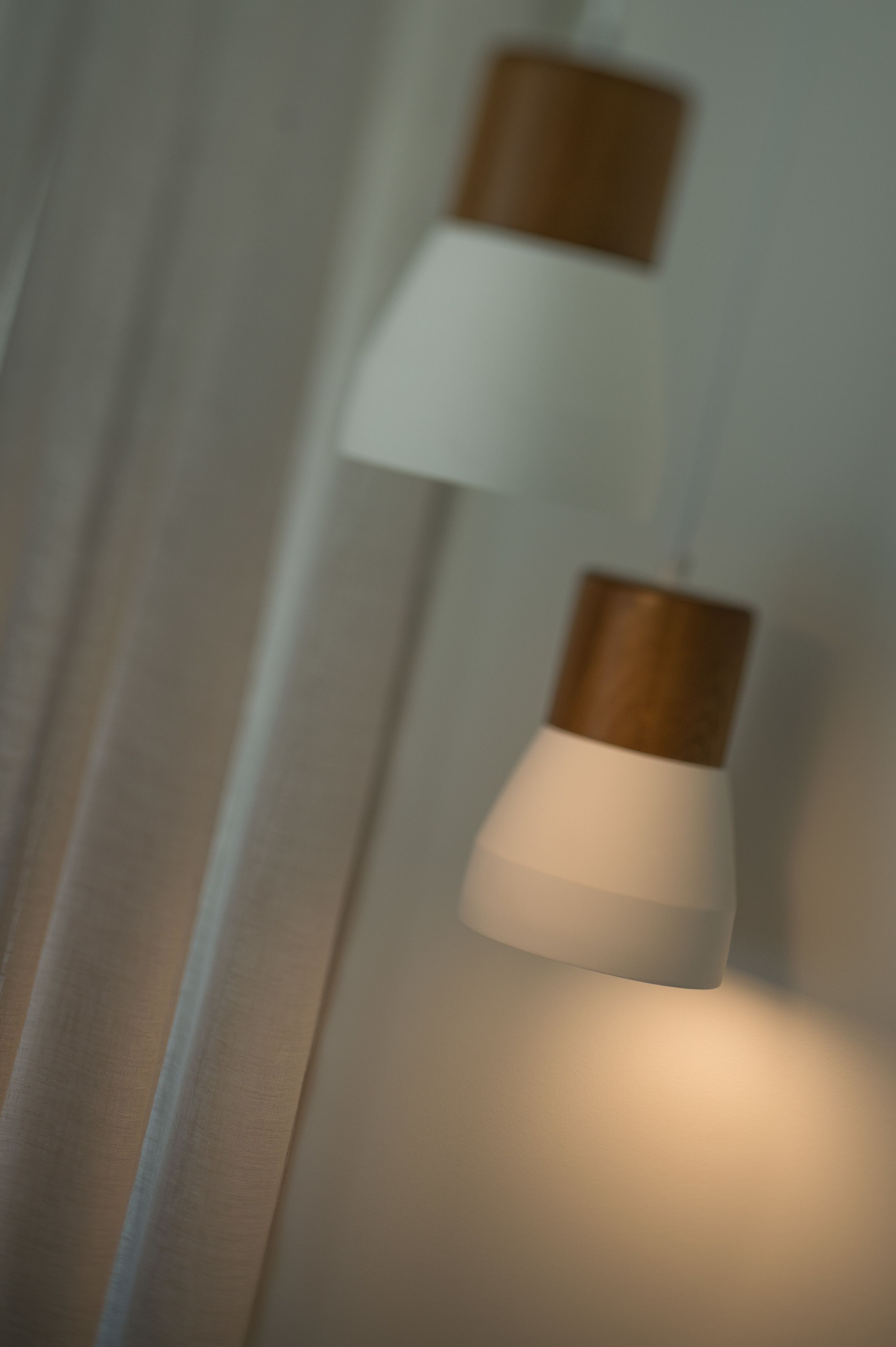 Gros plan d’un luminaire fixé au mur, doté d’un dessus en bois et d’une base blanche.