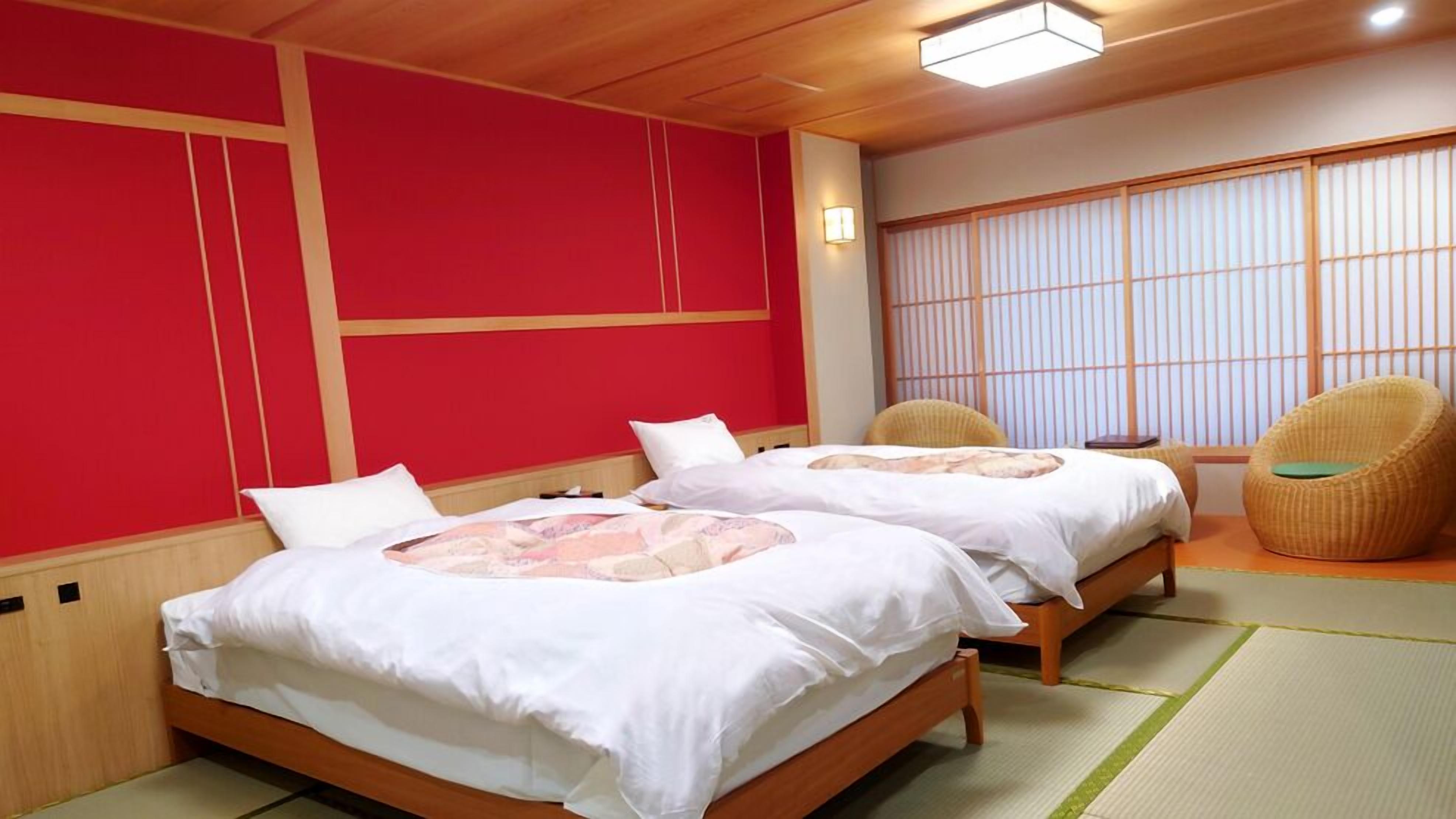Quarto com duas camas, uma porta tradicional japonesa deslizante e uma cadeira de fibra vegetal.