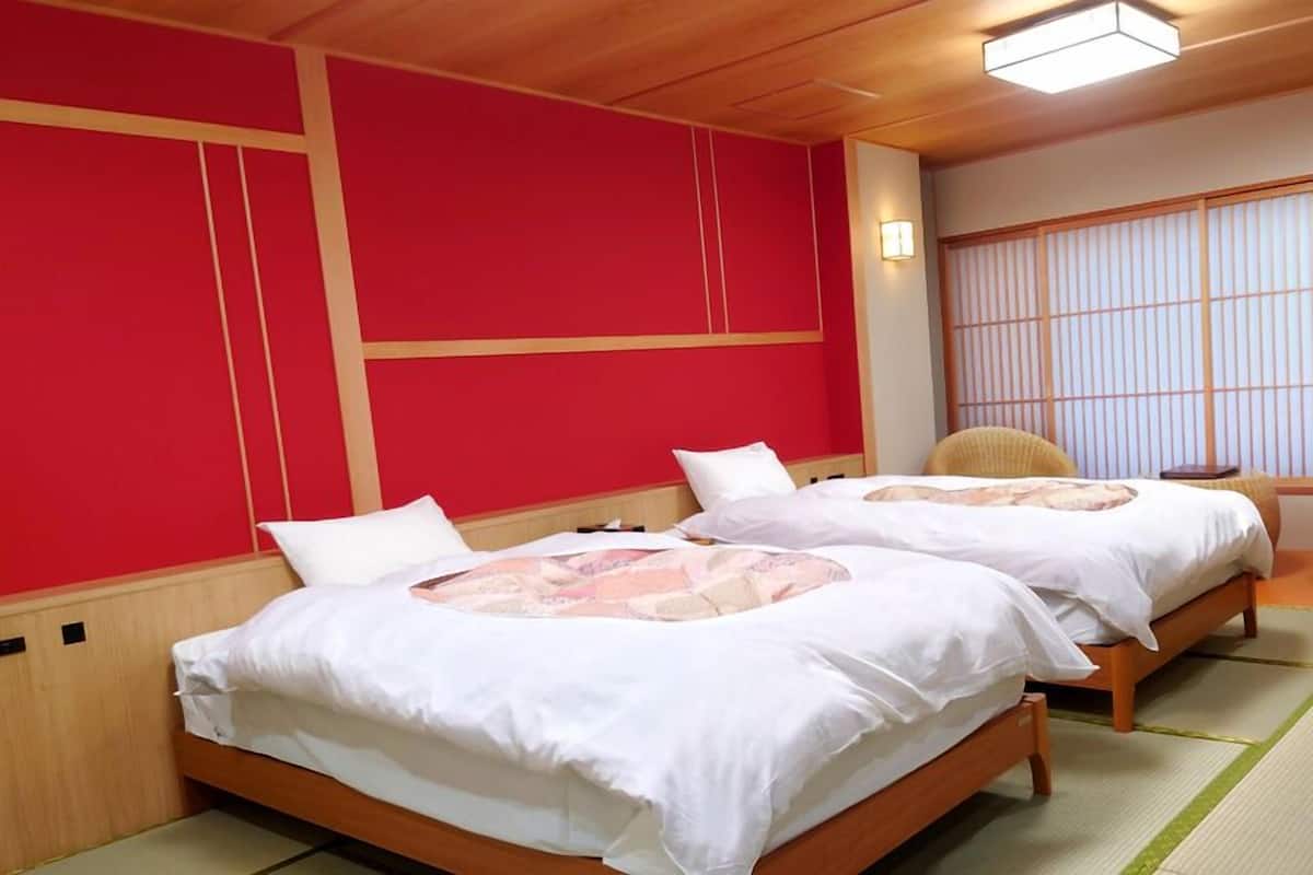Une chambre avec deux lits, une porte coulissante de style japonais traditionnel et une chaise en osier.