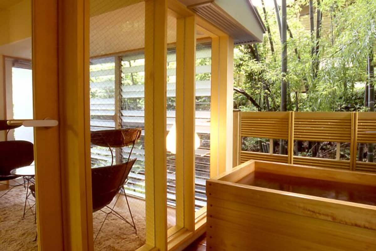 Una bañera de madera con vistas a un bosque de bambú.