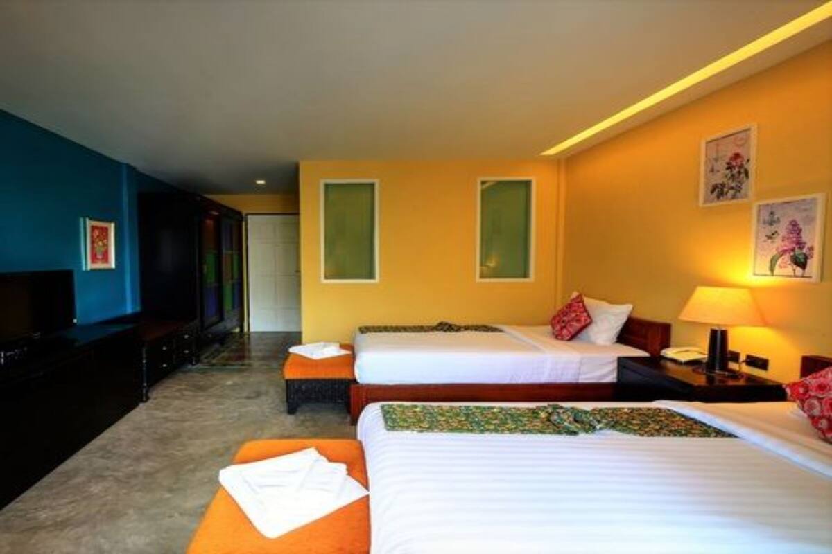 Habitación de hotel con dos camas, un televisor y un escritorio con lámpara.