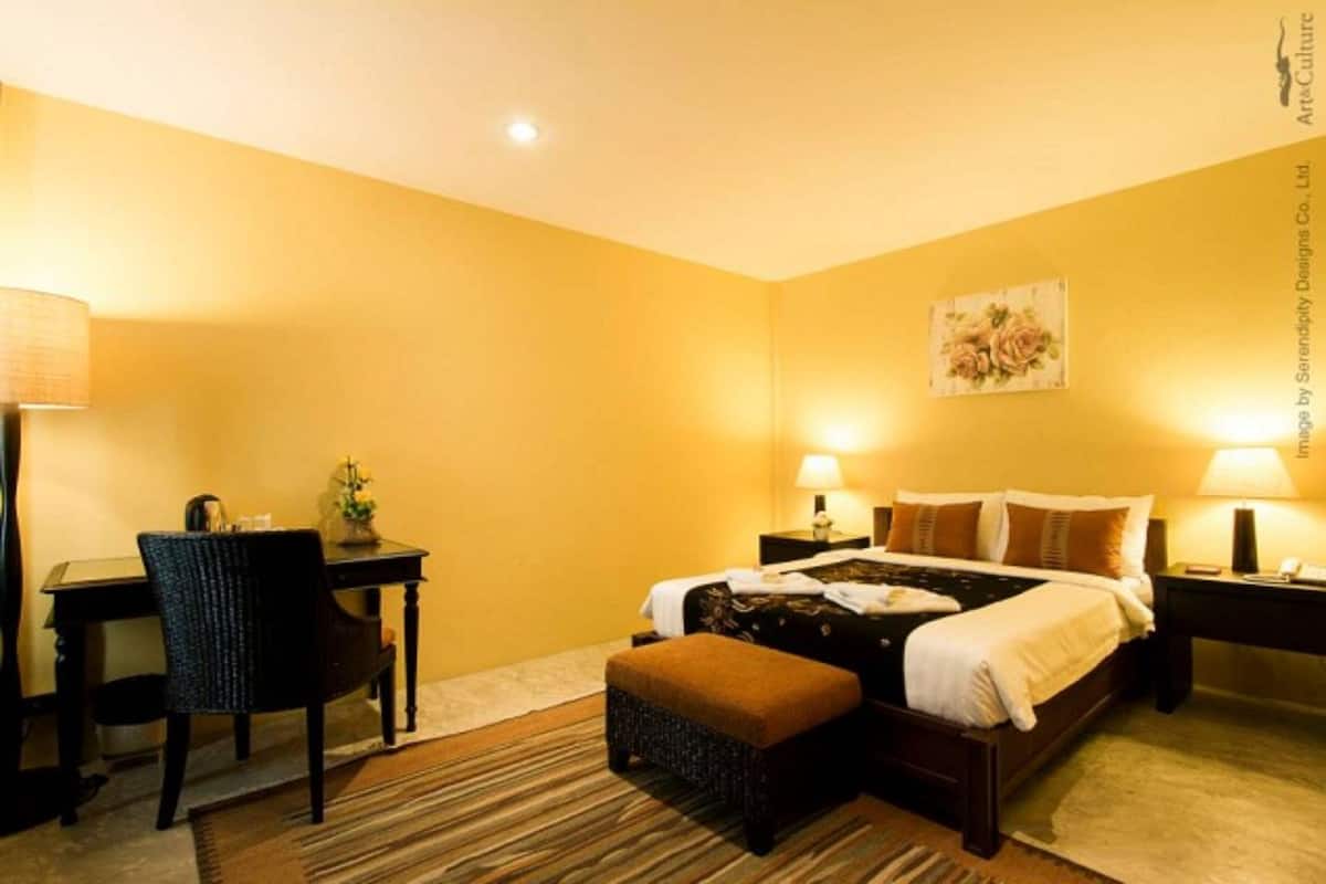Una habitación de hotel con cama, mesitas de noche, un escritorio y una silla.