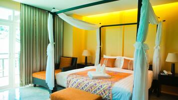 A four-poster canopy bed with a floral bedspread, a bedside table with a lamp, and a view of the outdoors through a large window.