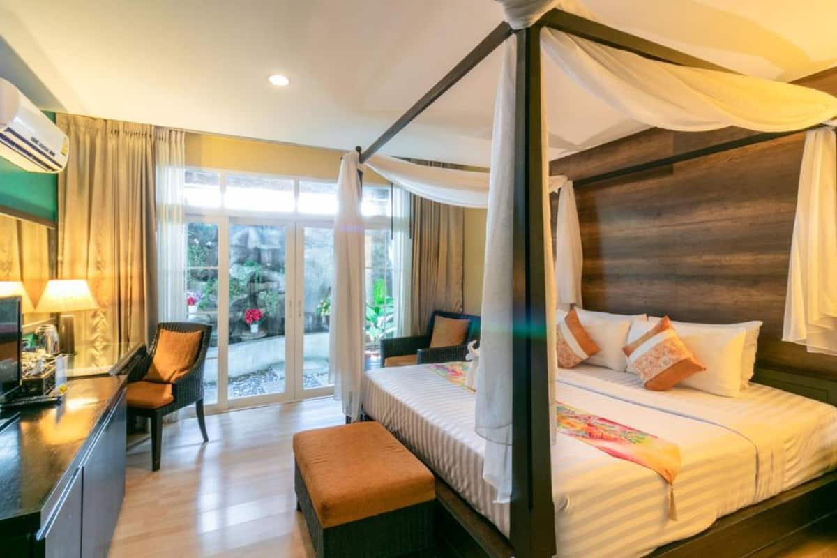 Una cama con dosel y cortinas, un escritorio con silla y un ventanal grande con cortinas.