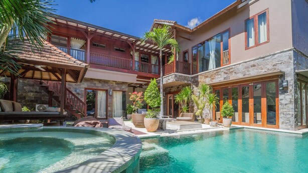 A two-story building with a swimming pool, outdoor seating, and a covered patio area. - Villa Martine (Seminyak)