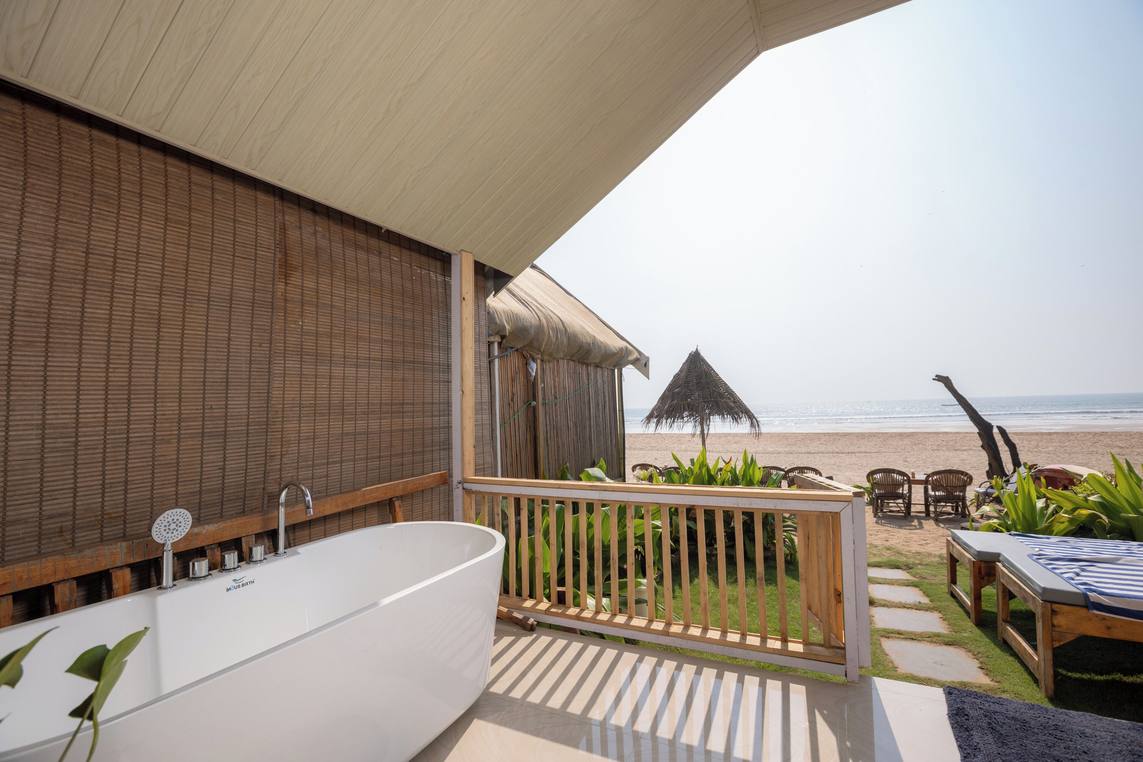 A bathroom with a bathtub, a shower, and a view of the beach.