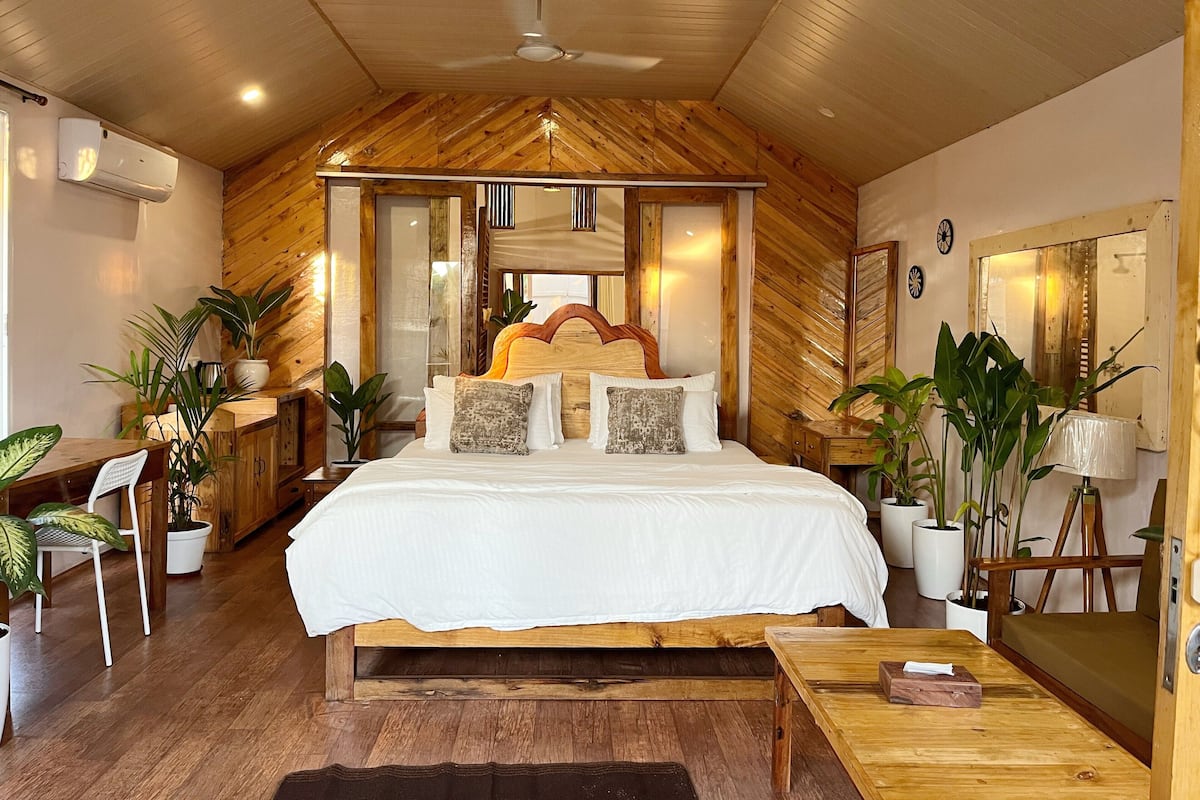 A bedroom with a wooden ceiling, a bed with white bedding, a wooden headboard, and a ceiling fan.