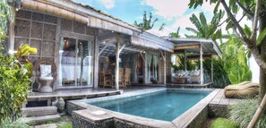 A poolside area with a wooden deck, outdoor seating, and a covered patio. - Villa Layla (Seminyak)