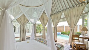 A bedroom with a bed, a chair, and a table. - Villa Laksmana Hideaway 2 (Seminyak)