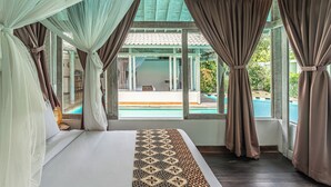 A bedroom with a bed, curtains, and a view of a pool. - Villa Laksmana Hideaway 2 (Seminyak)