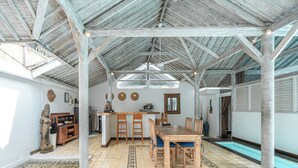 A spacious indoor area with a high ceiling, a dining table with chairs, a kitchen area, and a pool. - Villa Laksmana Hideaway 2 (Seminyak)