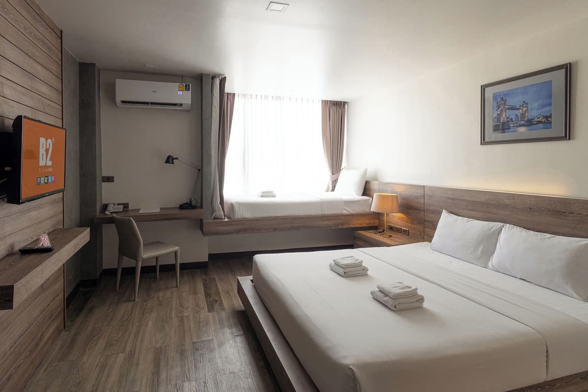 A hotel room with a bed, desk, chair, and a TV on the wall.