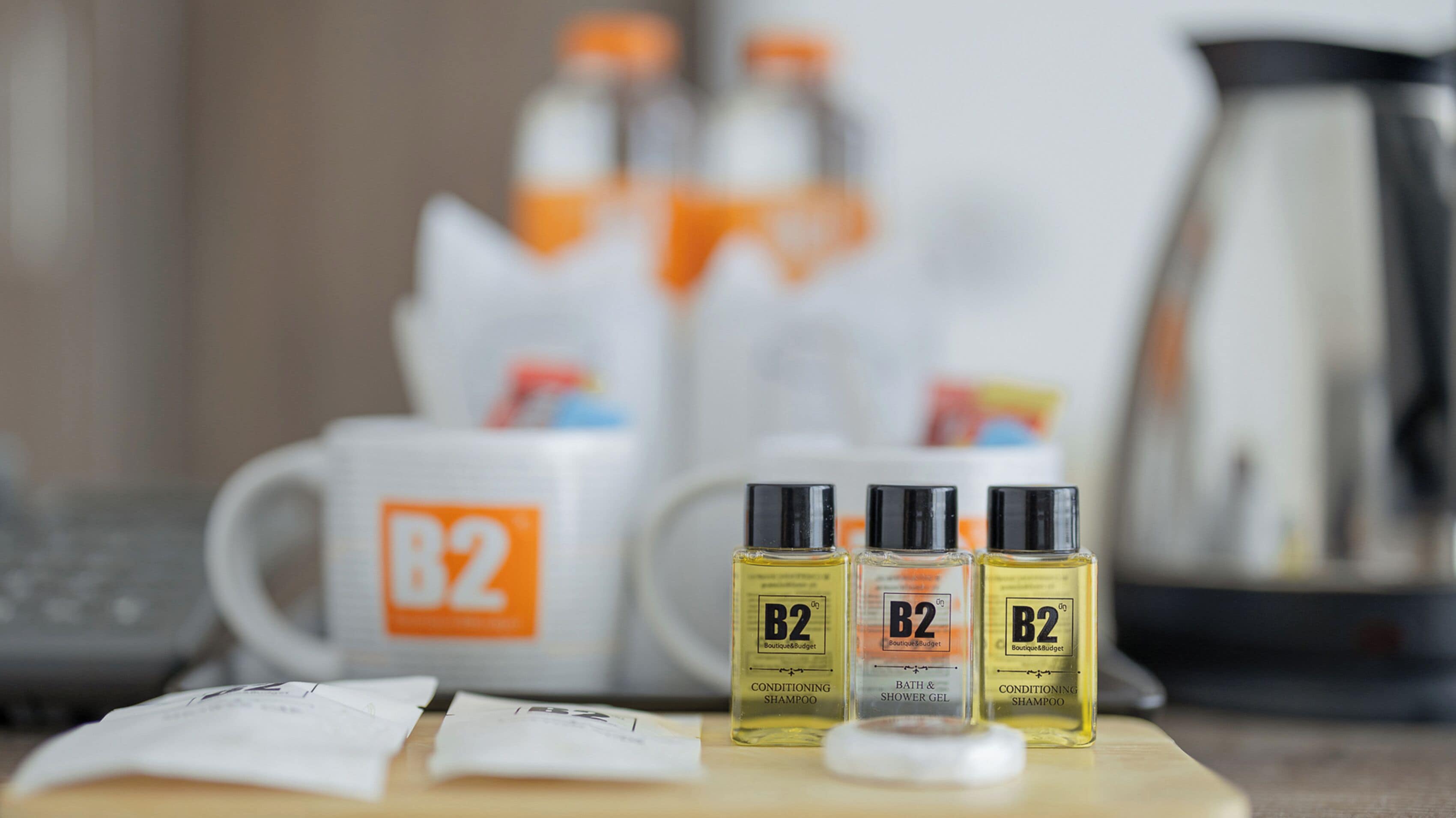 En badeværelsesbordplade med tre flasker B2 conditioning shampoo, en B2-kop og en kaffemaskine.