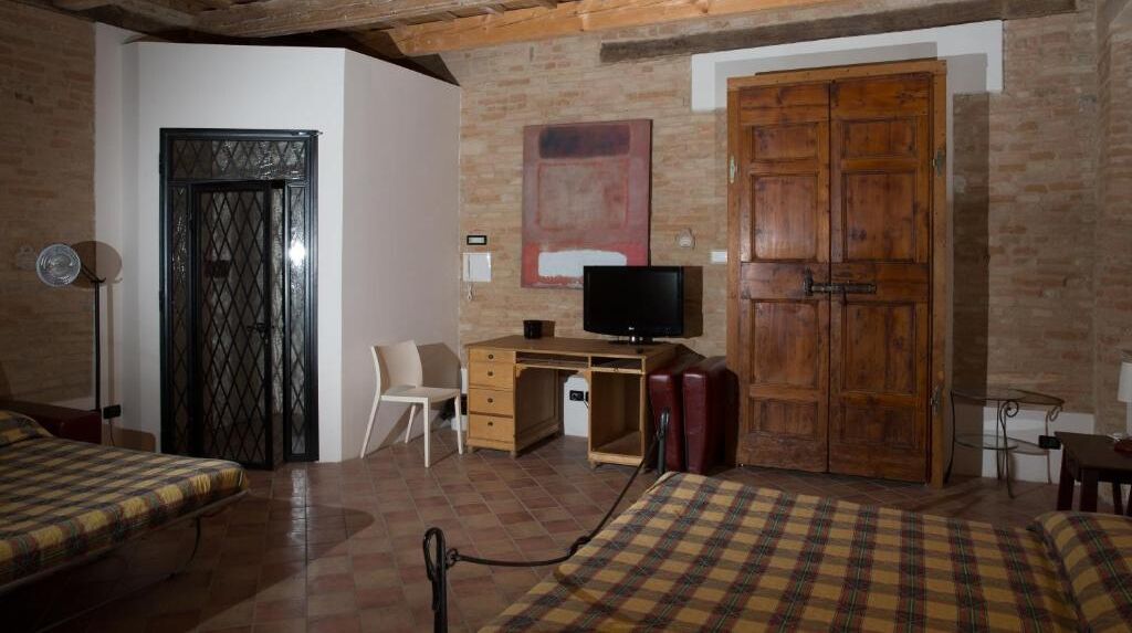 A bedroom with a bed, a desk, a television, a wardrobe, and a door.