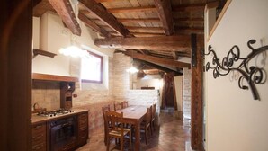 A rustic kitchen with wooden beams, a stone wall, and a tiled floor. - Palazzo Meraviglia - Albergo Diffuso (Corinaldo)