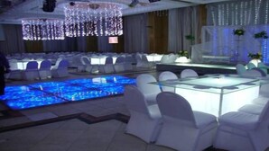 A banquet hall with round tables and chairs, a central stage, and a decorative pool area. - Minya Hotels of the Armed Forces (El Minya)