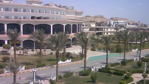 A multi-story building with a modern design, featuring balconies and a central courtyard with palm trees. - Minya Hotels of the Armed Forces (El Minya)