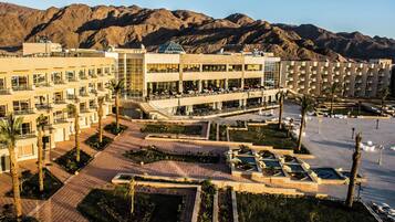 A hotel with multiple floors, outdoor seating areas, and a pool.