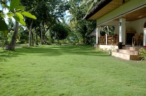 A well-maintained lawn with a thatched-roof structure and outdoor seating. - Neptune Diving Resort Santander (Santander)
