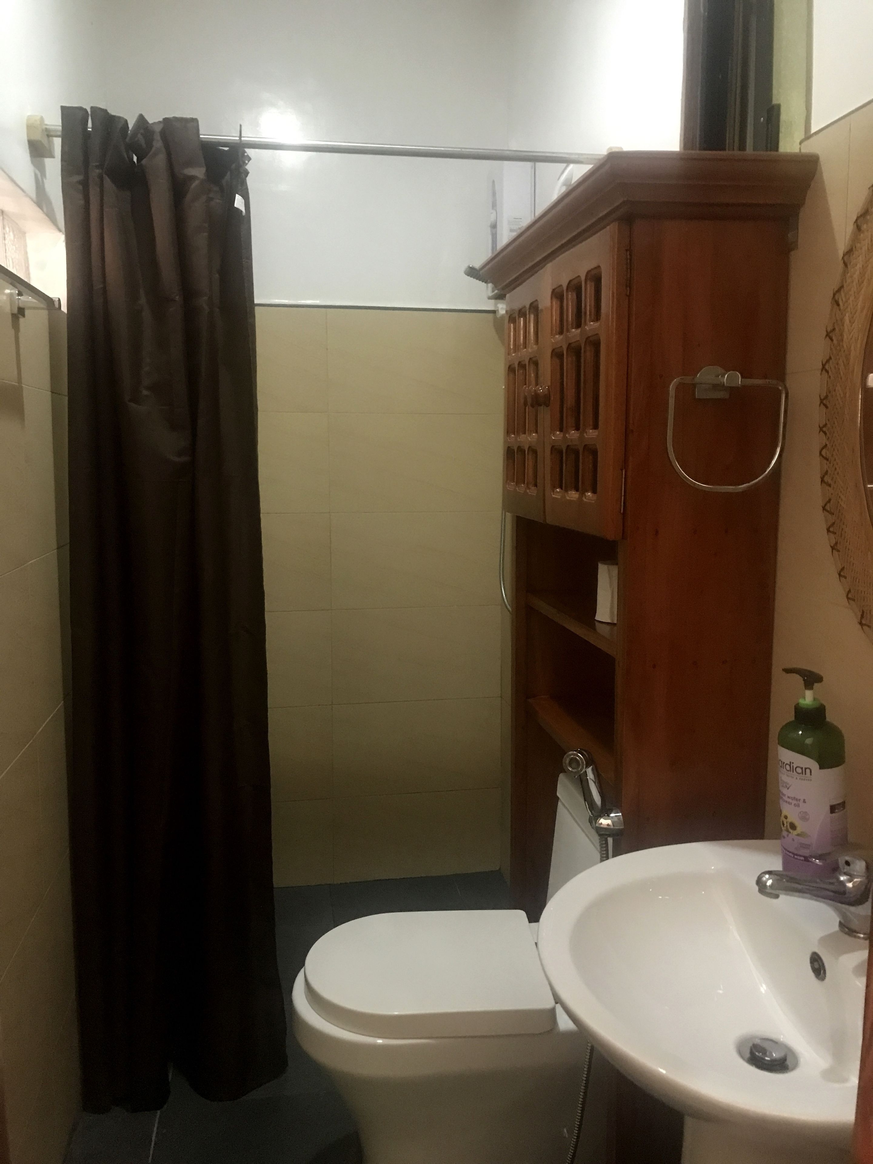 A bathroom with a toilet, sink, and cabinet.