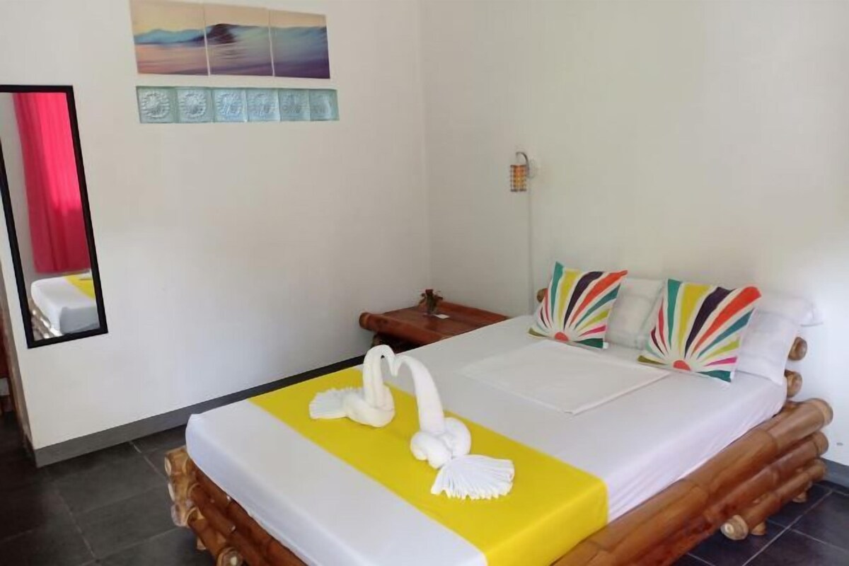 Habitación de hotel con una cama, una mesita de noche, un espejo y una pared con un cuadro.