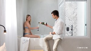A man and a woman in a modern bathroom with a shower, a towel, and a bottle of champagne. - Margaret of Naxos (Naxos)