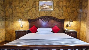 A hotel room with a stone-patterned wall, a large bed with white and red pillows, and two bedside tables with lamps. - Hotel Days Inn (Karachi)