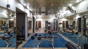 A gym with various exercise equipment, mirrors, and a blue carpeted floor. - Hotel Days Inn (Karachi)