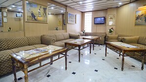 A hotel lobby with patterned sofas, wooden tables, and artwork on the walls. - Hotel Days Inn (Karachi)