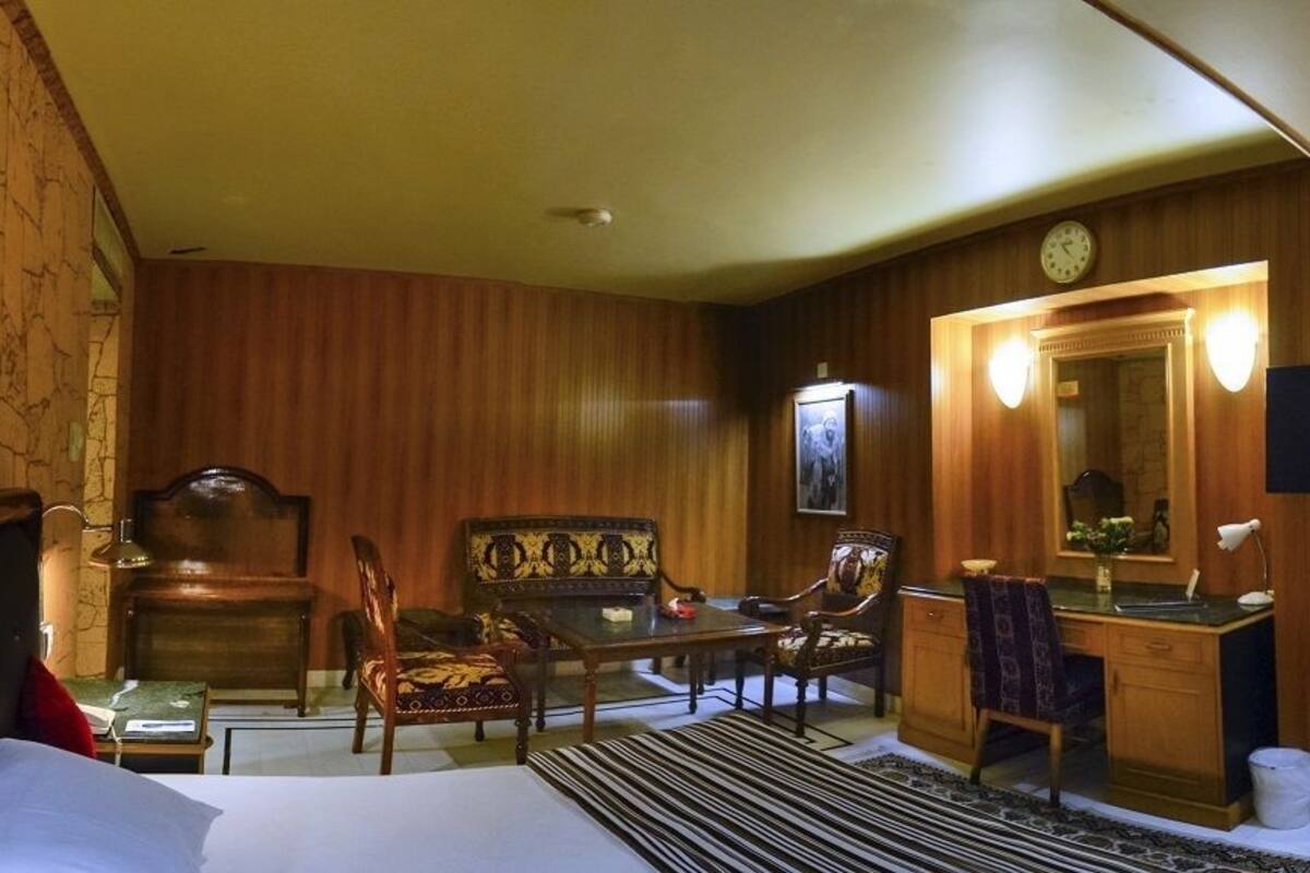 A hotel room with a bed, desk, chair, and a television.